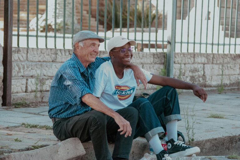 Two friends, an elder and a young adult, enjoying a sunny day sitting together outdoors in South Africa.